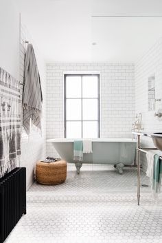 a white tiled bathroom with a tub and sink