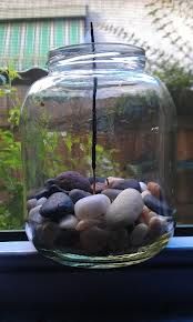 a glass jar filled with rocks sitting on top of a window sill