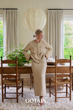 a woman standing in front of a table with chairs and a plant on top of it