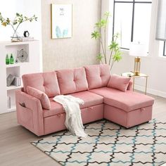 a living room with a pink sectional couch and white rugs on the hardwood floor