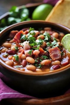 a close up of a bowl of food with beans and cilantro on the side