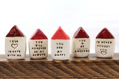 four ceramic crayons with words written on them in different shapes and sizes, lined up against a wooden surface