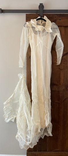 a white dress hanging on a wooden door