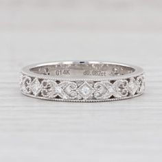 a white gold wedding band with an intricate design on the side and diamonds in the middle