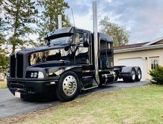 a black semi truck parked in front of a house