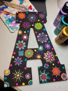 the letters are decorated with colorful flowers and dots on black paper, along with other crafting supplies