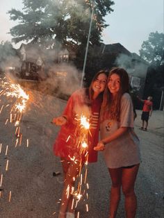 two girls standing next to each other holding sparklers