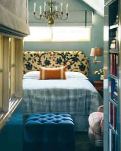 a bedroom with a bed, chandelier and bookshelf in the corner