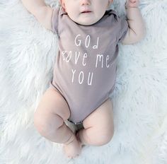 a baby laying on top of a white rug wearing a shirt that says god gave me you