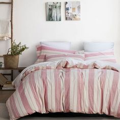 a bed with pink and white striped bedspread next to two pictures on the wall