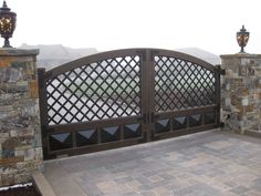 a gate that has some lights on top of it and is next to a stone wall