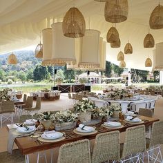 tables and chairs are set up in a tent for an outdoor event with hanging lights