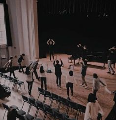 a group of people standing on top of a wooden floor in front of a stage