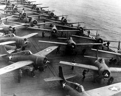 many planes are lined up on the deck of an aircraft carrier