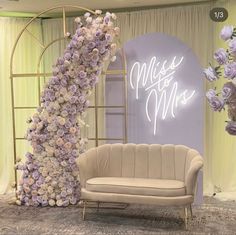 a couch sitting in front of a flower covered wall with the words miss and mrs on it