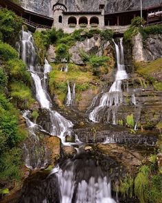 a waterfall in the middle of a building surrounded by greenery