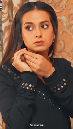 a woman in black shirt posing with her hands on her chest and looking at the camera