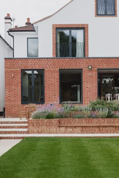 a brick house with flowers in the front yard and stairs leading up to the back door