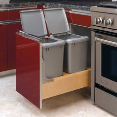 two trash cans are sitting on the pull out shelf in front of an oven and stove