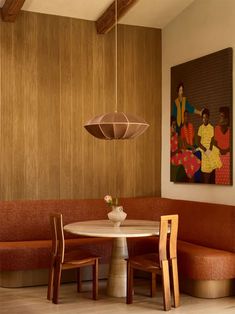 a dining room table with two chairs and a painting on the wall