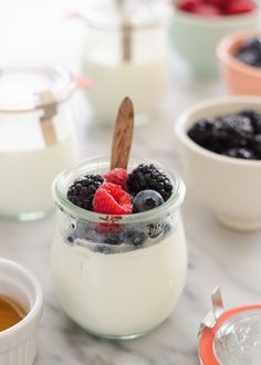 yogurt with berries and blueberries in a glass jar on a marble table