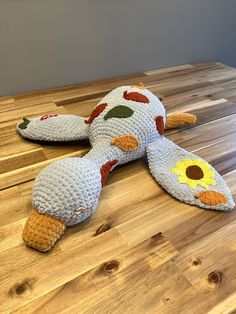 a stuffed animal laying on top of a wooden table