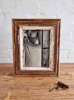 an old wooden frame with a key hanging from it's side on a table