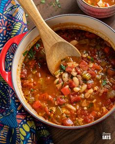 a wooden spoon in a bowl filled with beans and vegetables