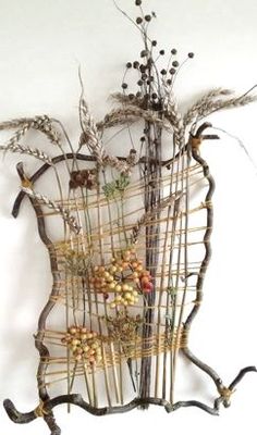 a sculpture made out of twigs and branches with berries on it's sides, sitting against a white wall