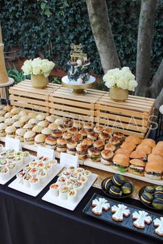 a table filled with lots of different types of sandwiches and cupcakes on plates