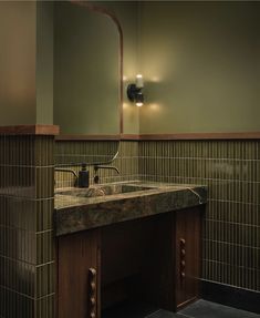 a bathroom with a sink and mirror next to a tiled wall in front of it