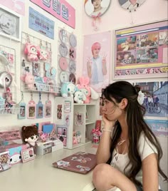 a woman sitting at a desk with stuffed animals on the wall