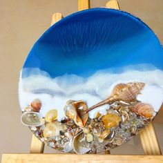 a blue plate with seashells on it sitting on top of a wooden easel