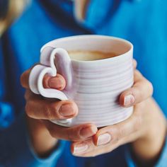 a woman holding a white coffee cup in her hands