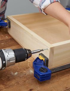 a person using a drill to attach the bottom part of a wooden box with screwdrivers