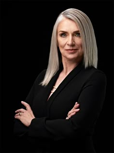 a woman with her arms crossed posing for a photo in front of a black background