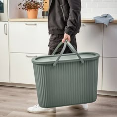 a man holding a large green container in the kitchen