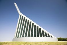 a large white building sitting on top of a lush green field under a blue sky