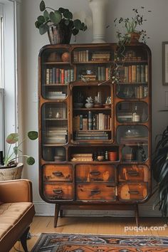 an old bookcase with lots of books and plants on it in a living room