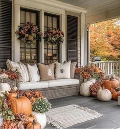 a porch decorated for fall with pumpkins and flowers on the couches, pillows and rugs