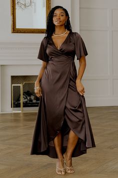 a woman in a brown dress standing on a wooden floor