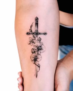 a cross and flowers tattoo on the right arm is shown in black ink with white background