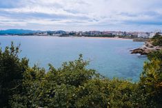 the water is calm and blue with some clouds in the sky above it, as seen from an overlook point