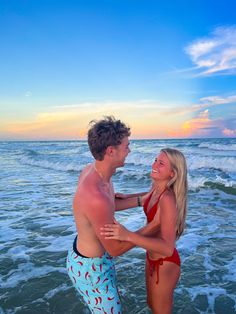 a man and woman standing in the ocean with their hands on each other's shoulders