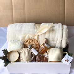 an open box with candles, soaps and other items in it on a white table cloth