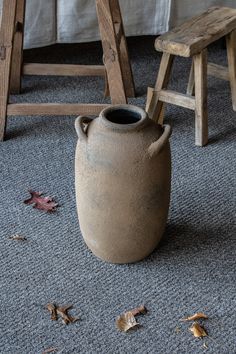 a vase sitting on the floor next to a wooden chair