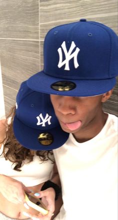 a young man wearing a new york yankees hat looking at his cell phone while taking a selfie