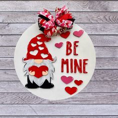 a white plate topped with a gnome cutout next to a red bow and some hearts