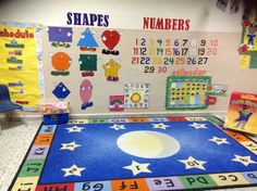 an area rug with numbers and shapes on the floor in front of a classroom wall