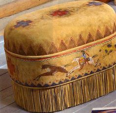 an ottoman sitting on top of a wooden floor next to pictures and plants in vases